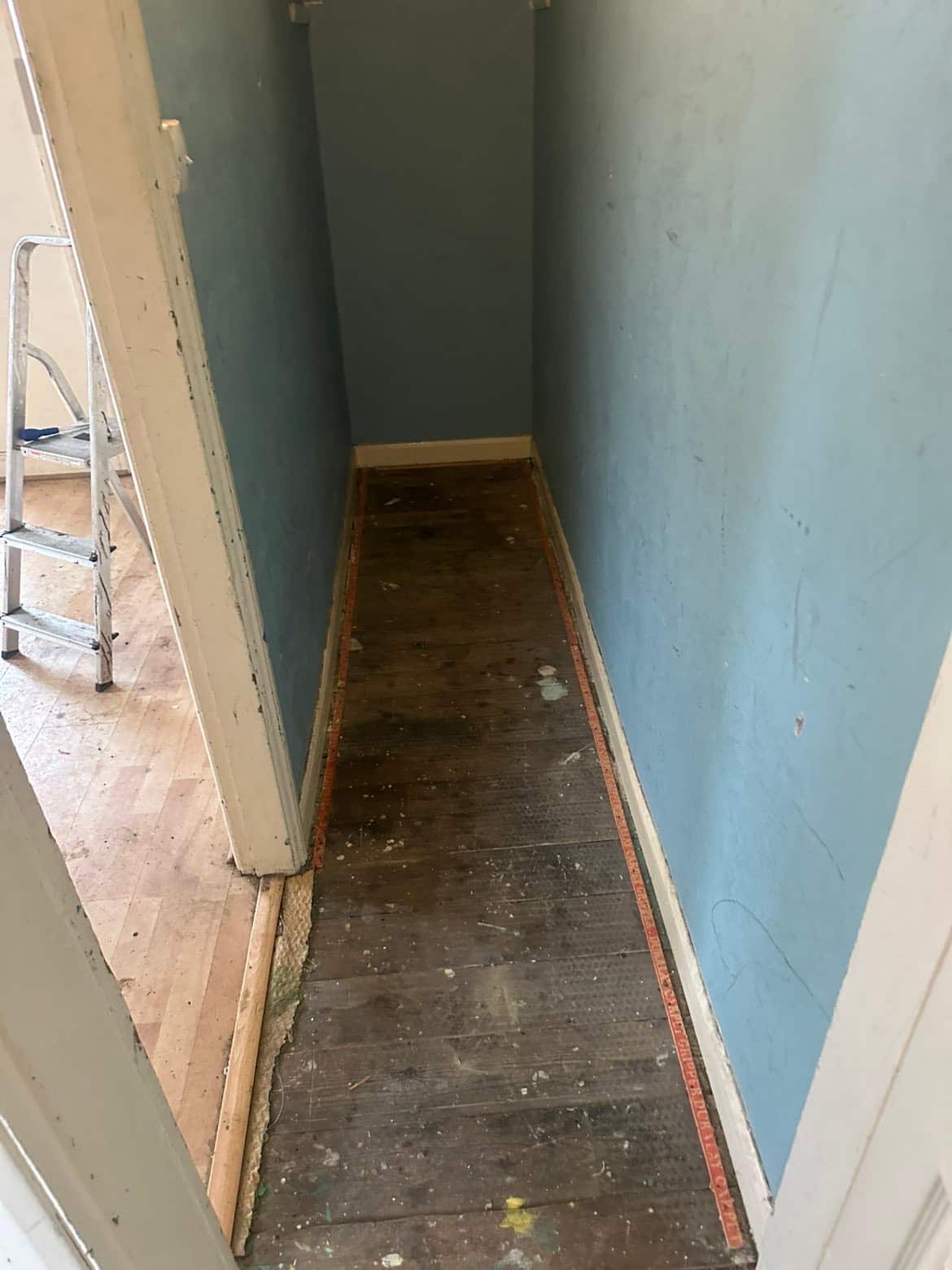 Hallway with carpet and underlay stripped back to bare floorboards, ready for new flooring