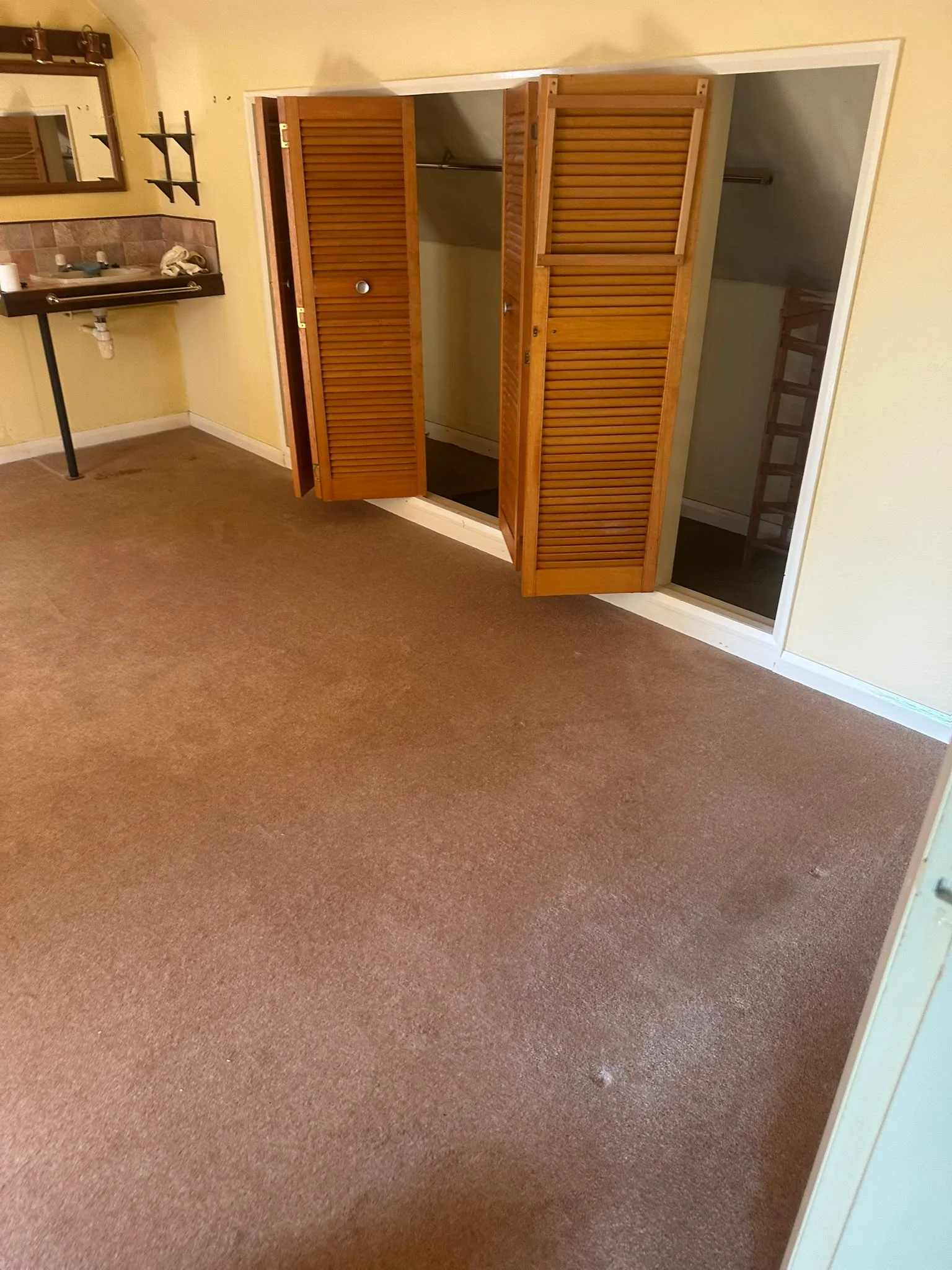 Attic bedroom after clearance, cleared back to bare carpet with fitted wardrobes