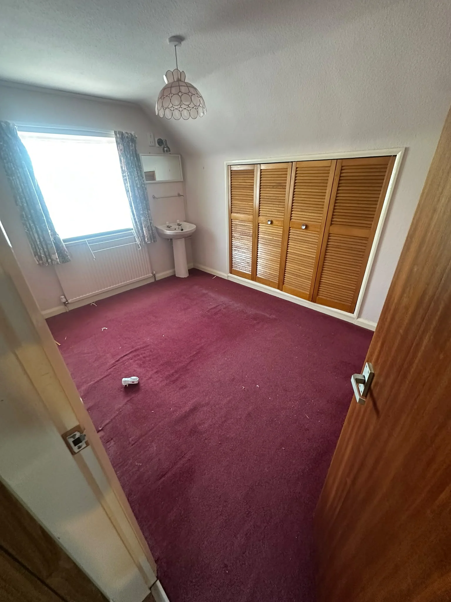 Bedroom after clearance, empty with just the sink and fitted wardrobes left in place