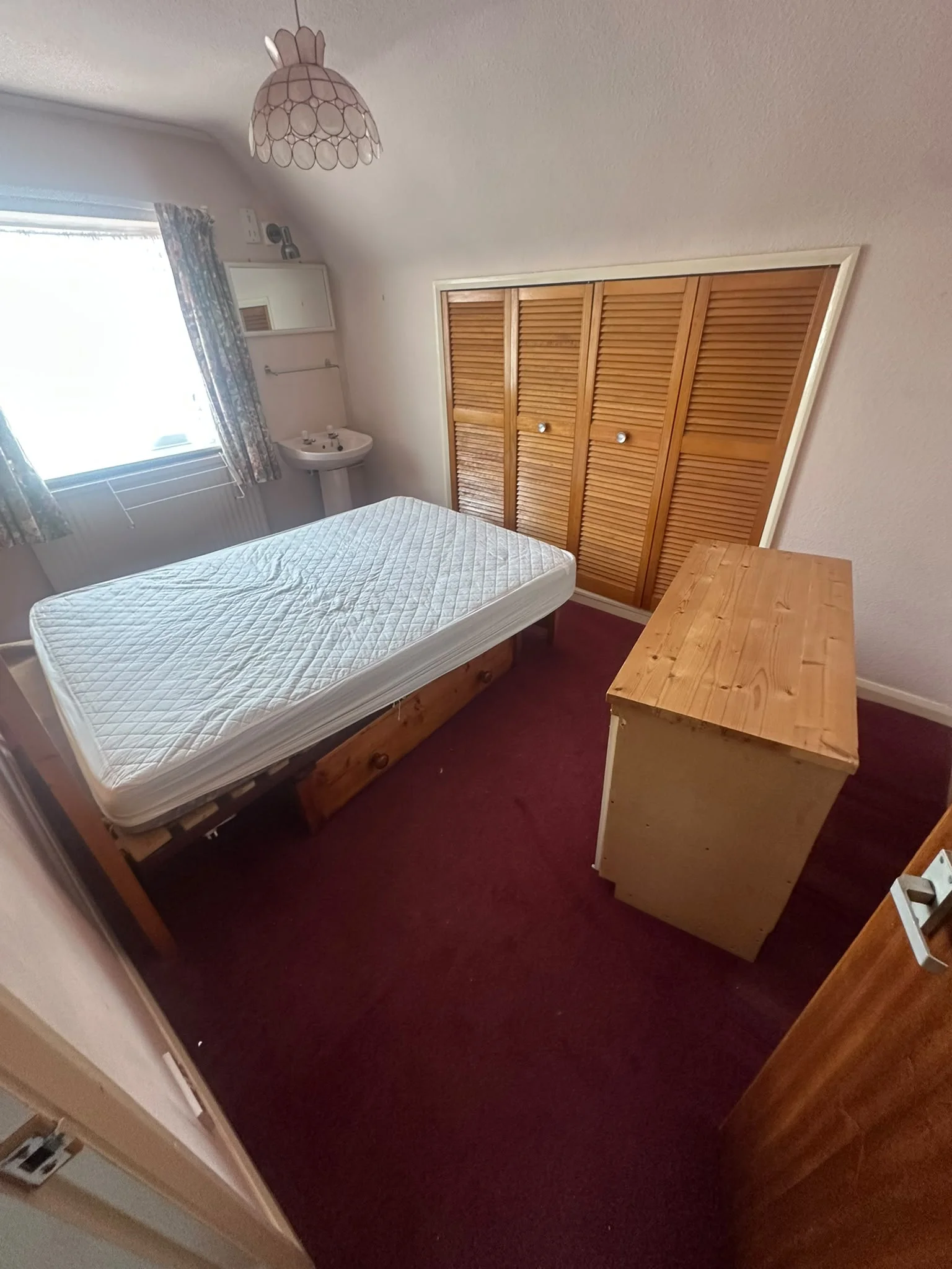 Bedroom before clearance with a mattress, chest of drawers and fitted wardrobes