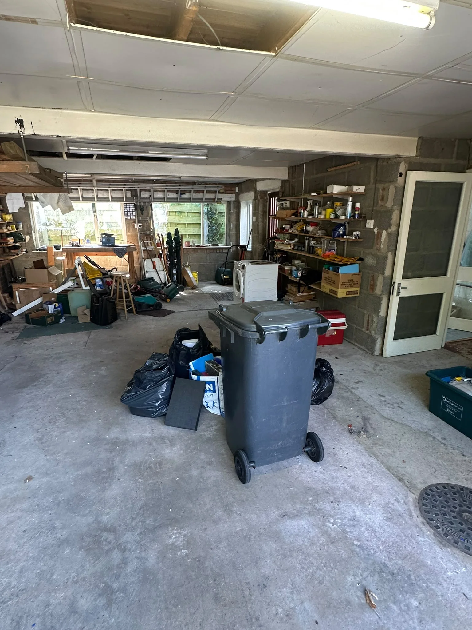 Garage full of tools, boxes and a wheelie bin before clearance