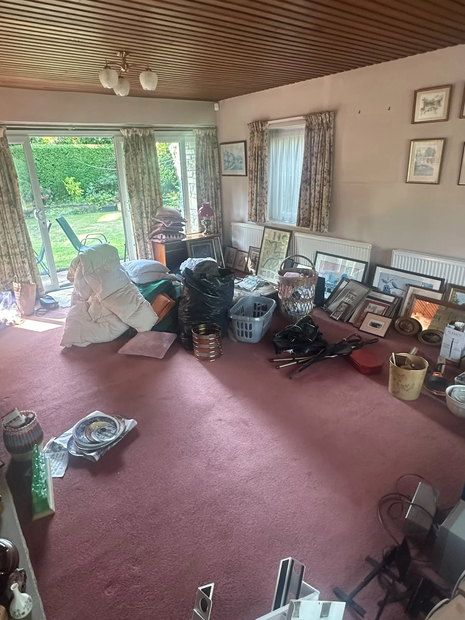 Living room before clearance in a York bungalow, dark red carpet with an antique sideboard and glassware