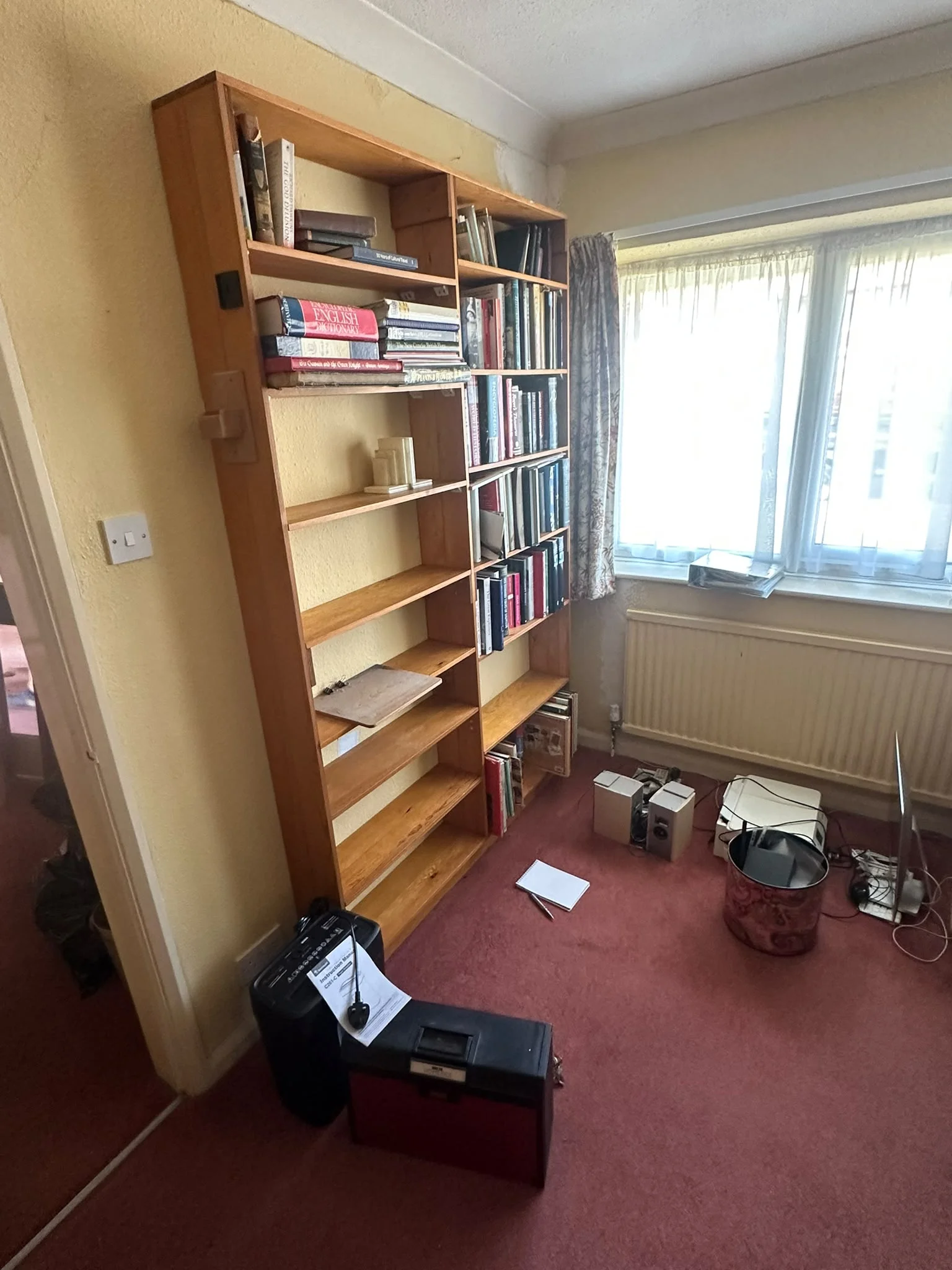 Home office before clearance with a full-height bookshelf and a shredder